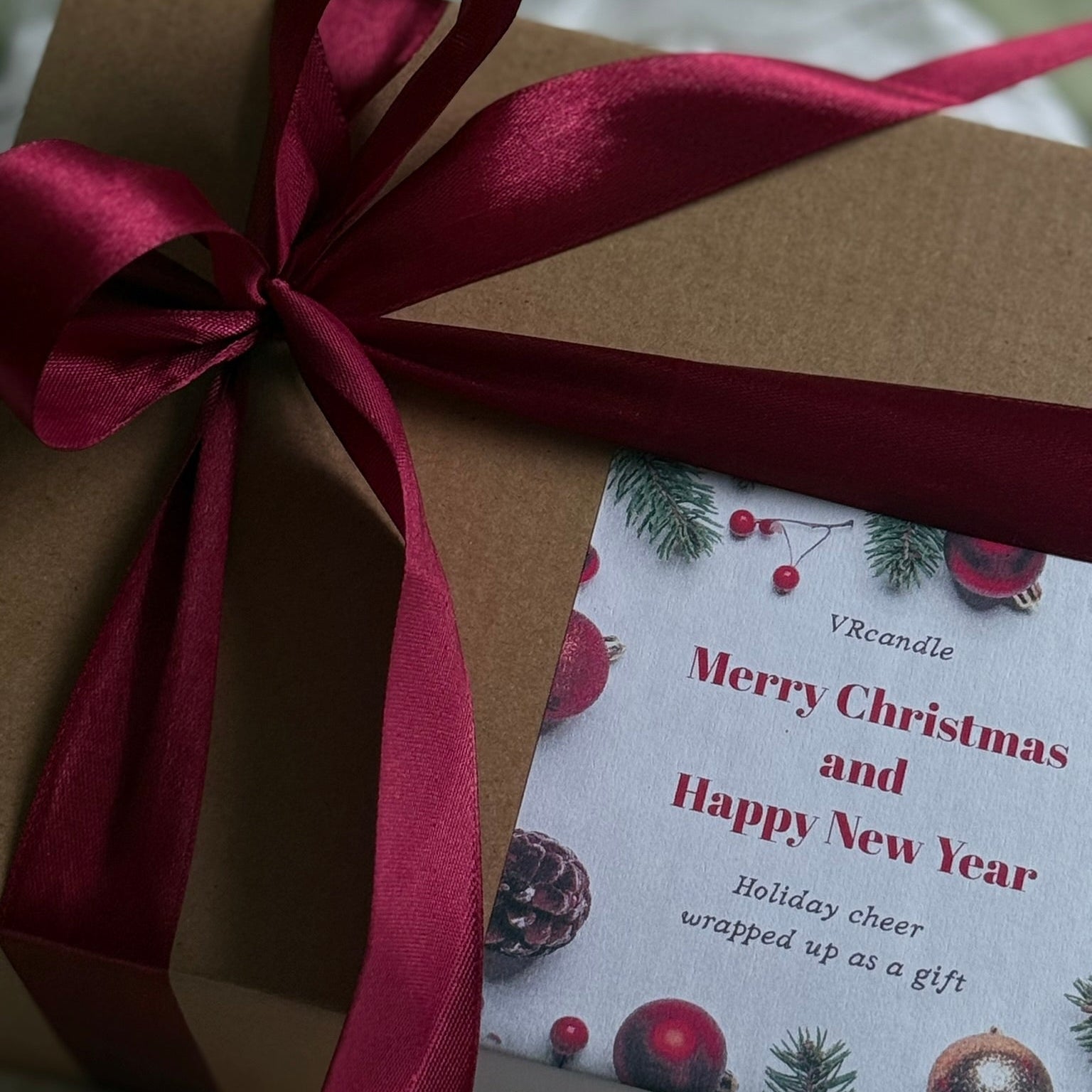Gift box with a red ribbon and a Christmas-themed card on a textured surface.