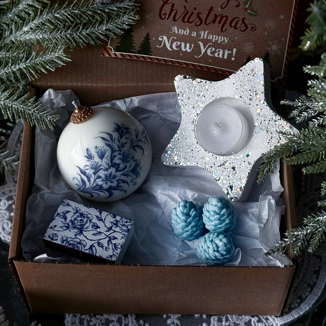 Decorative Christmas box with ornaments and a candle, featuring a &