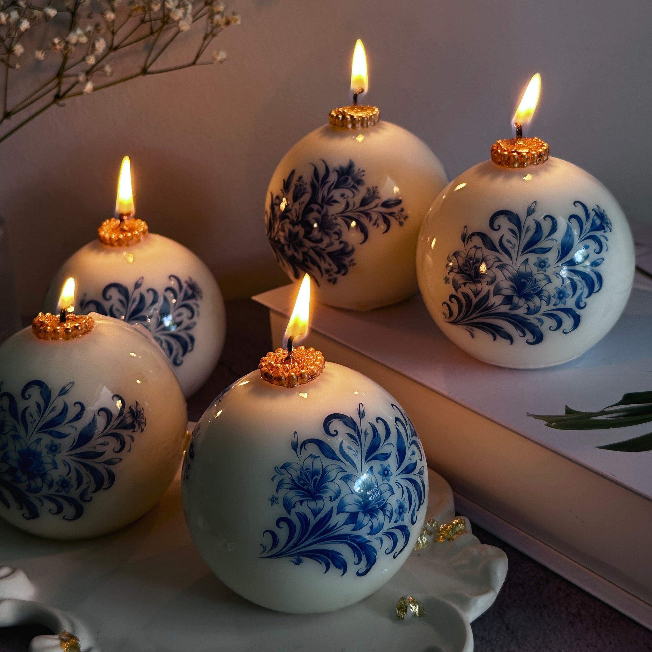 Decorative candles with blue floral patterns on a white surface.